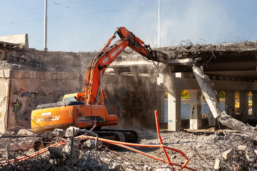 Ouvrier en tenue haute visibilité et casque de sécurité blanc effectue des travaux de rénovation sur mur extérieur en béton
