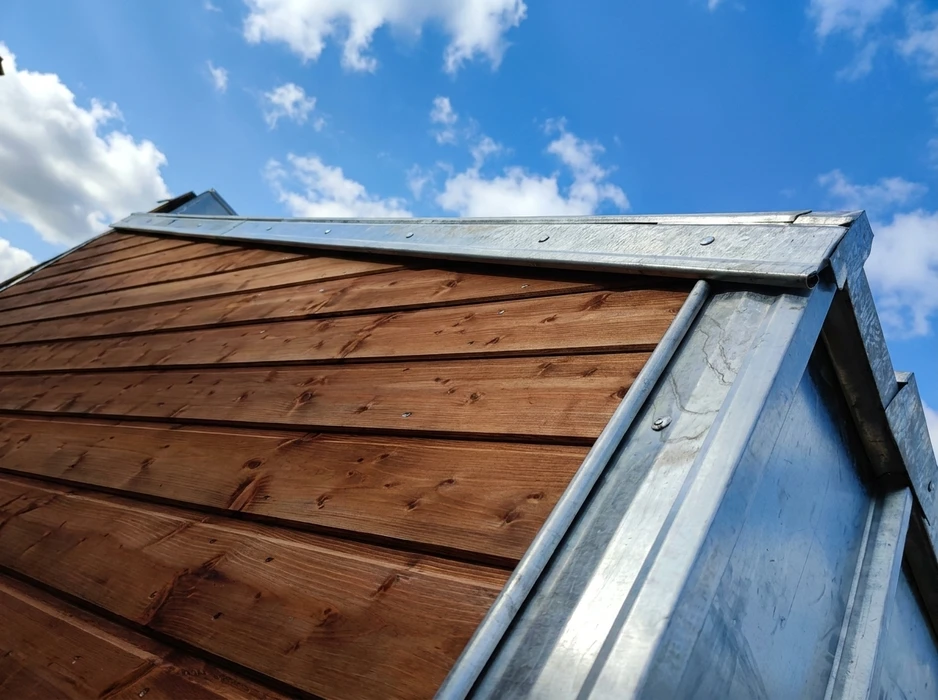 Vue en contre-plongée d'un bardage en bois résineux traité, teinte brun chaud, pose horizontale à claire-voie