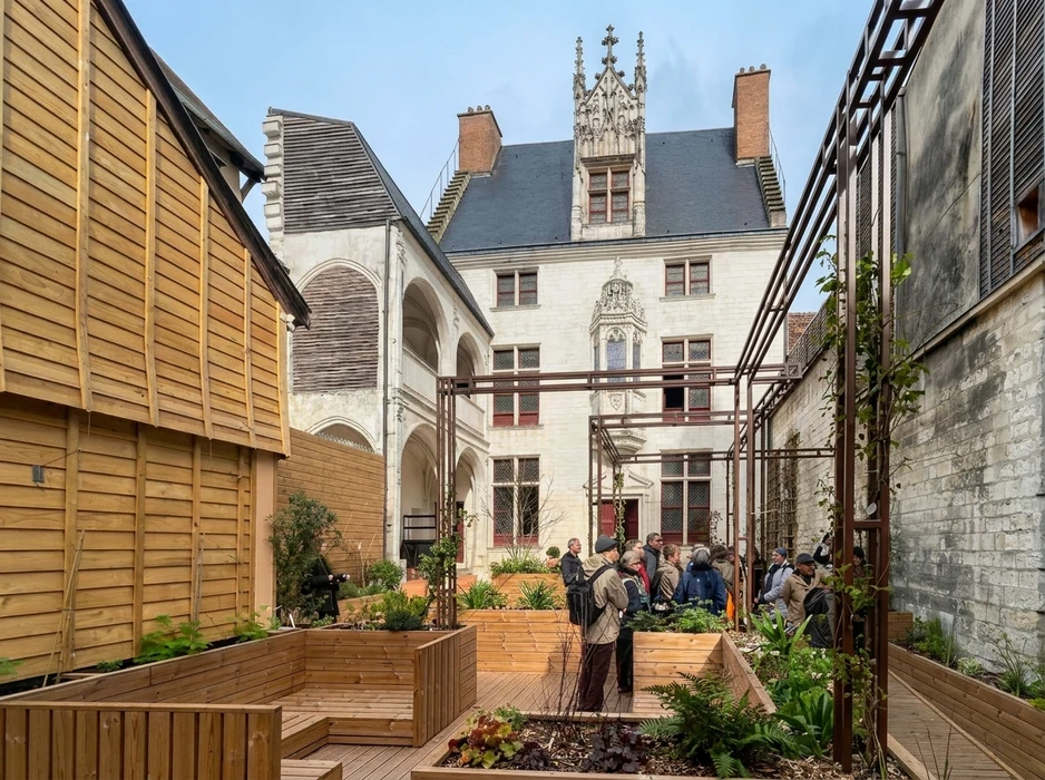 Groupe de visiteurs dans une cour intérieure d'un hôtel particulier gothique franco-Renaissance en tuffeau blanc, avec tour à pinacles
